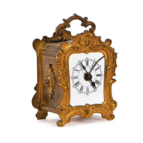 Sub.:15 - Lote: 212 -  Reloj de viaje en metal dorado con motivos vegetales y de rocalla cincelados, Francia, primera mitad del s.XX. 