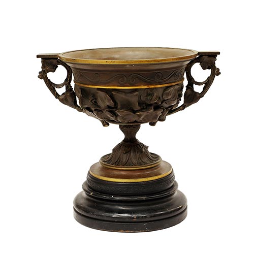Sub.:25 - Lote: 176 -  Gran copa en bronce con asas y decoracin vegetal en relieve. Apoya sobre peana de madera. s. XIX.