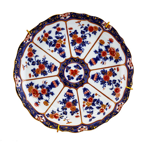Sub.:10-On - Lote: 786 -  Plato en porcelana esmaltada, con jarrones de flores y greca geomtrica azul en el ala.