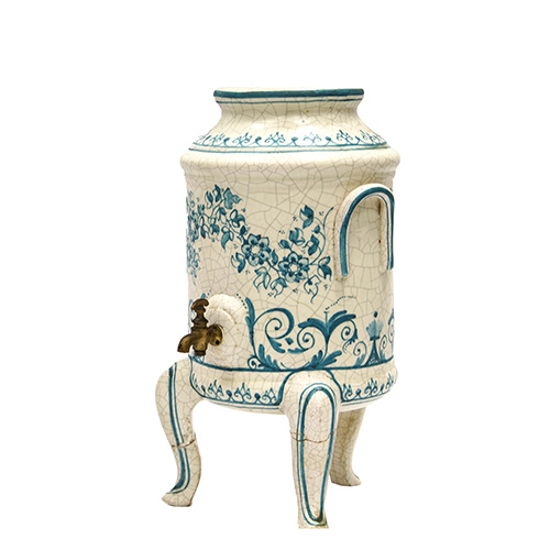 Sub.:10 - Lote: 1521 -  Depsito de agua en cermica con decoracin floral azul sobre fondo blanco y grifo en bronce. Dos patas consolidadas.