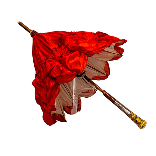 Sub.:14-On - Lote: 1614 -  Sombrilla en seda roja con mango emulando marfil de dioses egipcios. Desperfectos en el mango.