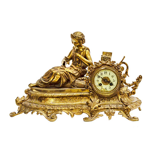 Sub.:18 - Lote: 336 -  Reloj en bronce dorado con figura recostada leyendo, esfera en esmalte con numeraci�n ar�biga. Desperfectos en la esfera. Con p�ndulo y llave.