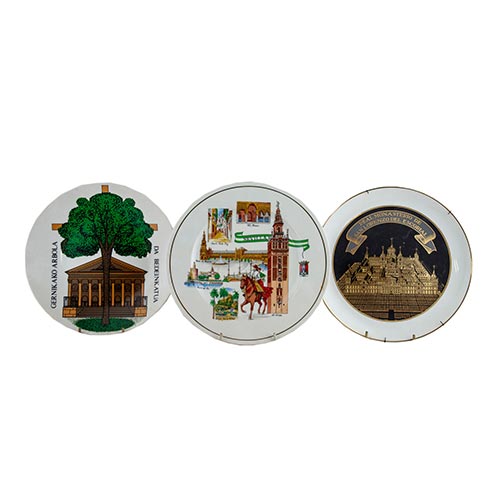 Sub.:2-On - Lote: 654 -  Juego de tres platos en porcelana, con representaciones simblicas de ciudades. Sevilla, El Escorial y El rbol de Guernika.