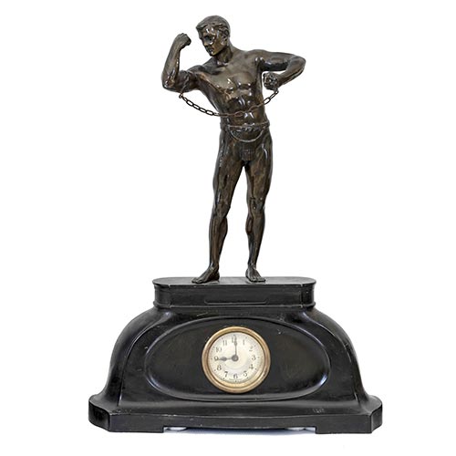 Sub.:26 - Lote: 445 -  Reloj de sobremesa en calamina representando un hombre forzudo. ca. 1900, poca Art Dec.