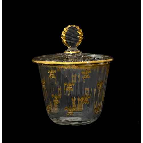Sub.:28 - Lote: 1128 -  Vasito con su tapa en cristal tallado y decoracin de flores de lis doradas. Rotura en el borde interior de la tapa.
