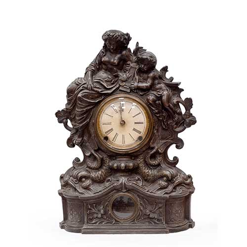 Sub.:34 - Lote: 224 -  Reloj de sobremesa en calamina con ni�os m�sicos sobre delfines. En el interior etiqueta de New York