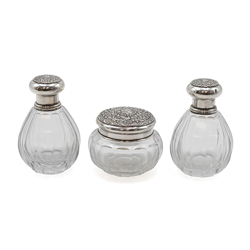 Sub.:38 - Lote: 1465 -  Pareja de botellas esencieros y tarro en cristal tallado y tapones en plata con motivos romanos Peso 196 gr